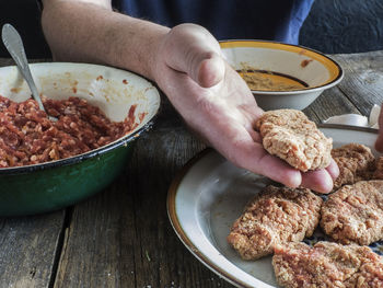 Cropped image of hands mixing batter by minced meat at table