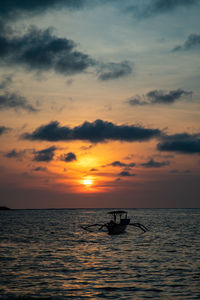 Silhouette boat in sea against sky during sunset