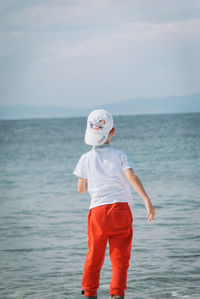 Boy walking in sea against sky