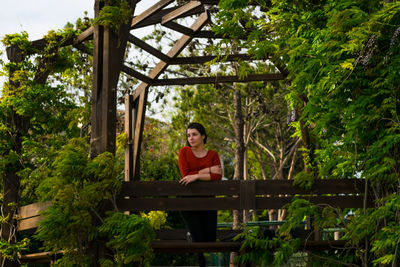 Young woman standing in gazebo amidst trees in park