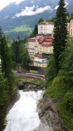 Scenic view of river and waterfall by buildings against mountain