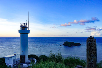 Lighthouse by sea against sky