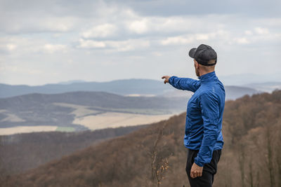 Young active man pointing direction into the distant valley