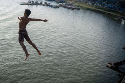 Full length of shirtless man jumping in sea