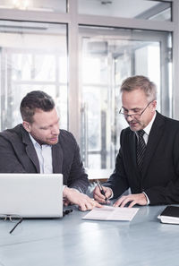 Businessman showing partner to sign document at restaurant table