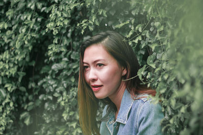 Portrait of young woman against plants