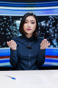 Portrait of young woman standing against wall