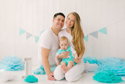 A beautiful young happy family with a one-year-old child, the father hugs the mother, the child 