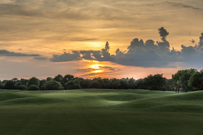 Scenic view of a golf course against sky during sunset