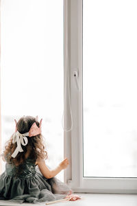 Woman looking through window at home