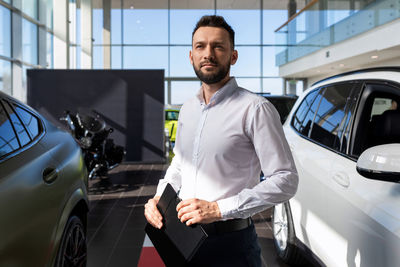 Portrait of salesman standing in car showroom