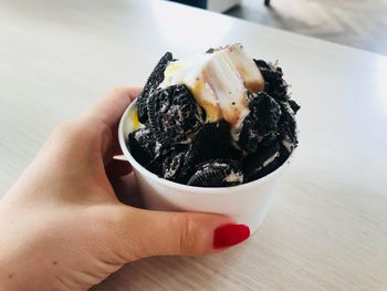 Close-up of hand holding frozen yoghurt with oreo 