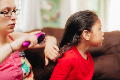 Mother combing daughters hair