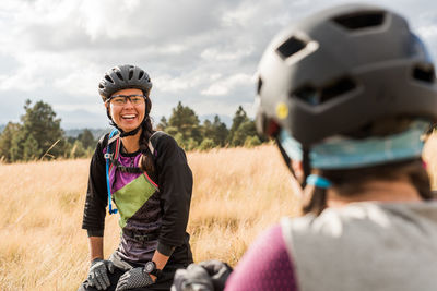 Lauging female mountain biker sitting in meadow