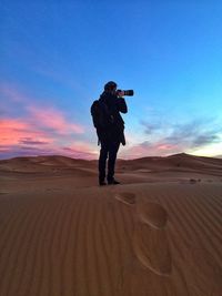 Rear view of woman taking picture in desert