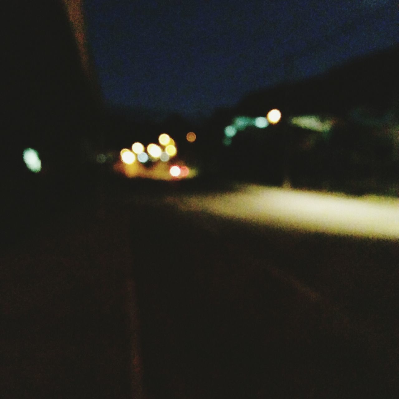 DEFOCUSED LIGHTS ON ROAD AT NIGHT