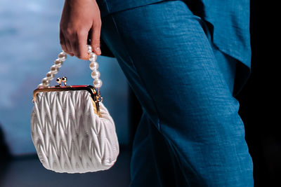 Close up fashionable details of a white clutch with beads in a woman's hand. elegant accessories