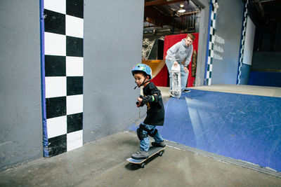 Skater kid looks focused after skating down a ramp, instructor watches