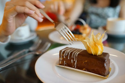 Cropped hand of woman holding fork over pastry