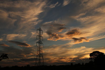 Low angle view of silhouette communications tower against sky at sunset