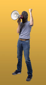 Full length of man standing against yellow background