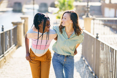 Smiling friends embracing while standing outdoors