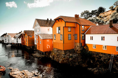 Buildings by river against sky