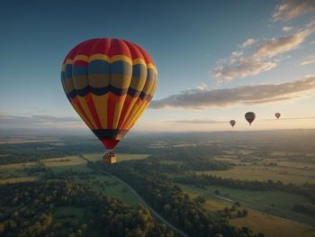 Hot air balloons flying over landscape against sky during sunset