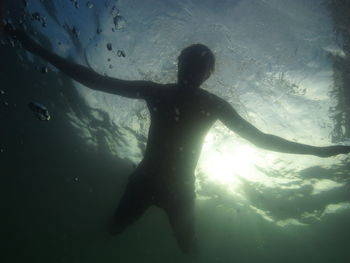 Rear view of silhouette man swimming in sea