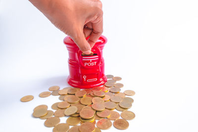 Close-up of hand holding coins over white background