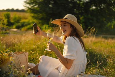 Girl with a glass of champagne or white wine makes a selfie on the phone. people using technology.