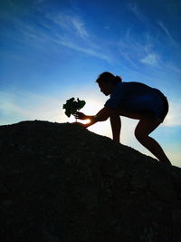 Man photographing rock on mountain against sky