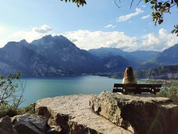 Girl sitting on the bench looking at lake panorama
