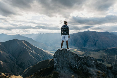 Rear view of man standing on mountain against sky