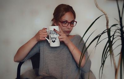 Portrait of mid adult woman holding mug while sitting at home