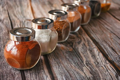 Various colorful herbs and spices in glass container on wooden background