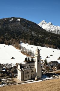 Buildings by mountain against sky during winter