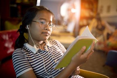 Teenage girl reading book while sitting on chair