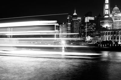 Light trails on road against buildings at night