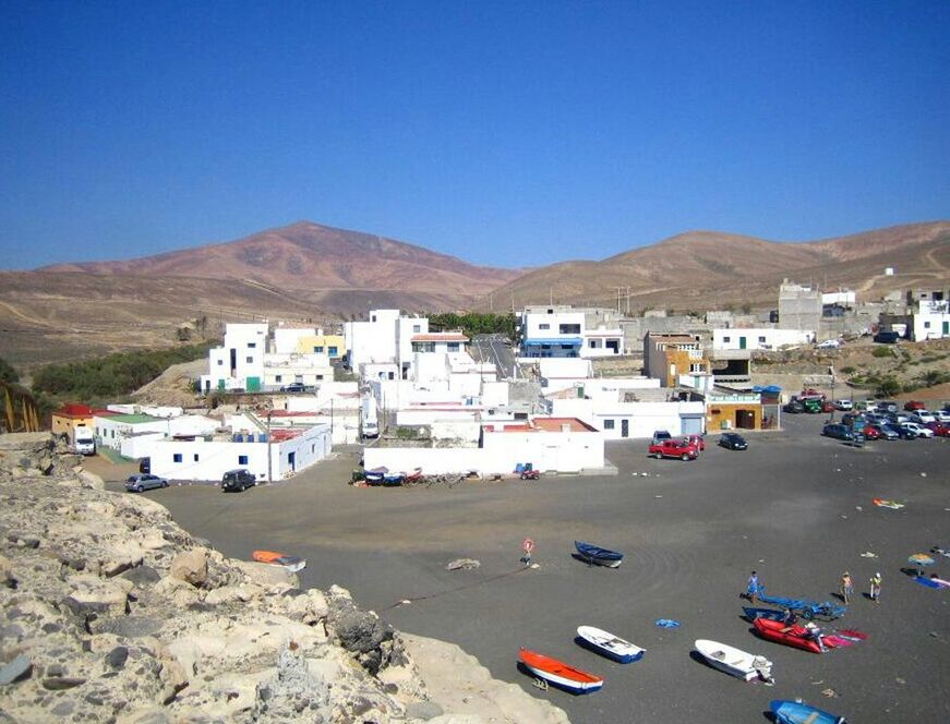 mountain, clear sky, transportation, mode of transport, building exterior, car, copy space, built structure, architecture, land vehicle, blue, road, mountain range, house, day, nautical vessel, sunlight, outdoors, incidental people, high angle view