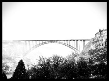 Bridge over calm sea against clear sky