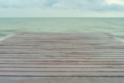 Surface level of wooden pier at sea against sky