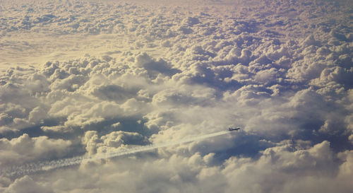 High angle view of airplane flying over clouds