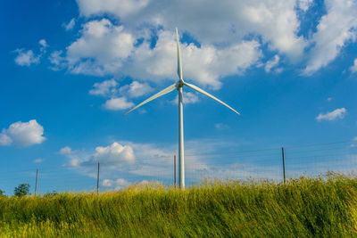 Wind turbines on field against sky