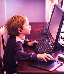 Side view of boy using computer at table