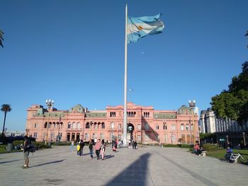 Group of people in town square against clear blue sky