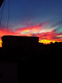 Silhouette buildings against sky at sunset