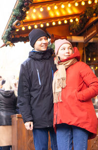 Young pair standing and smiling at christmas market in europe.