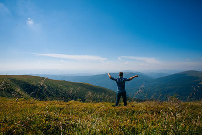 Rear view of person standing on field against mountain range