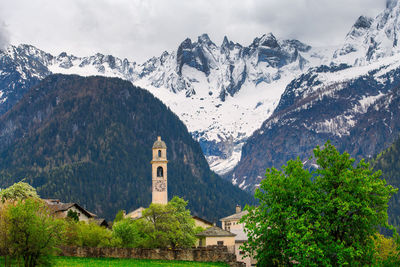 Scenic view of building and mountains against sky during winter